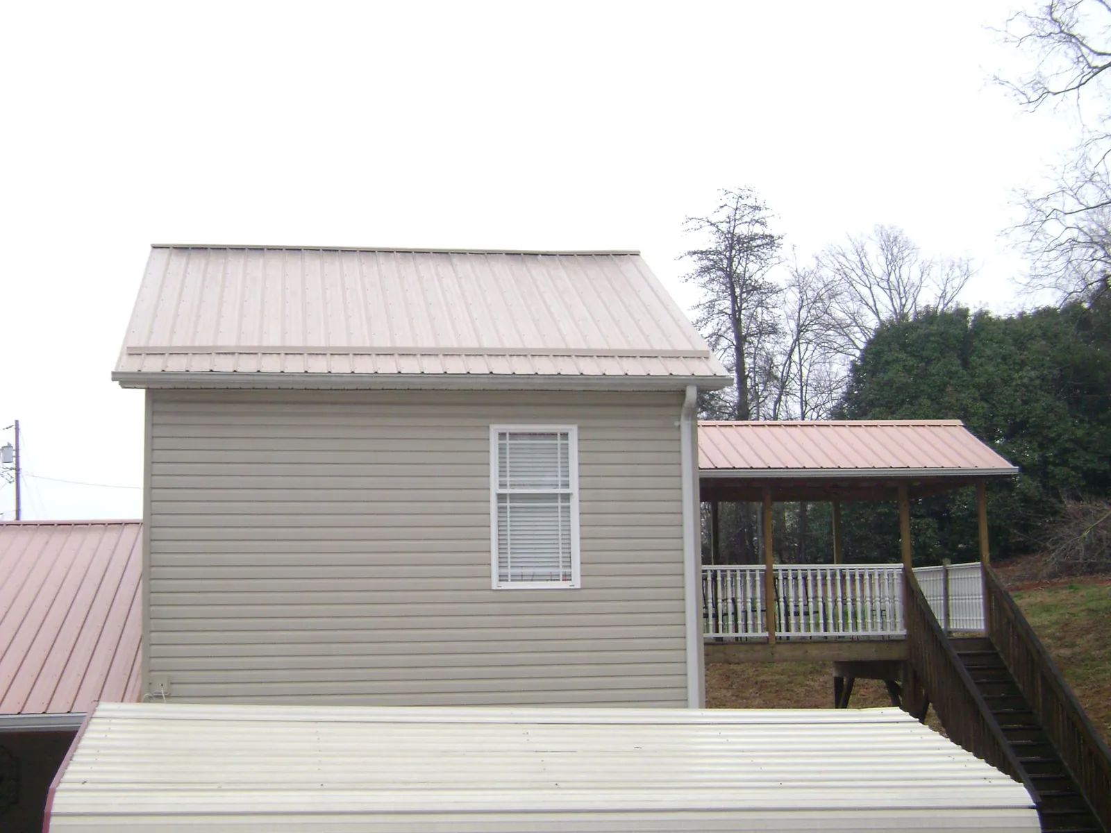 Tan metal roofs on a two story addition and attached porch, from a Roof Replacement job in New Berlin
